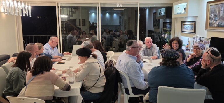 משתתפים משחקים במשחקי קופסה וקלפים סביב שני שולחנות בסדנה של משחקים מחוץ לקופסה