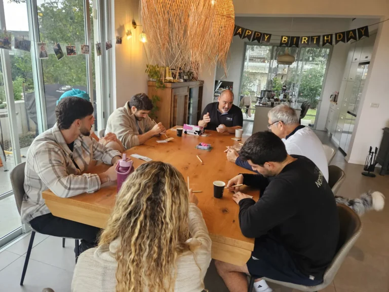 משפחה וחברים משחקים יחד סביב שולחן באירוע פרטי
